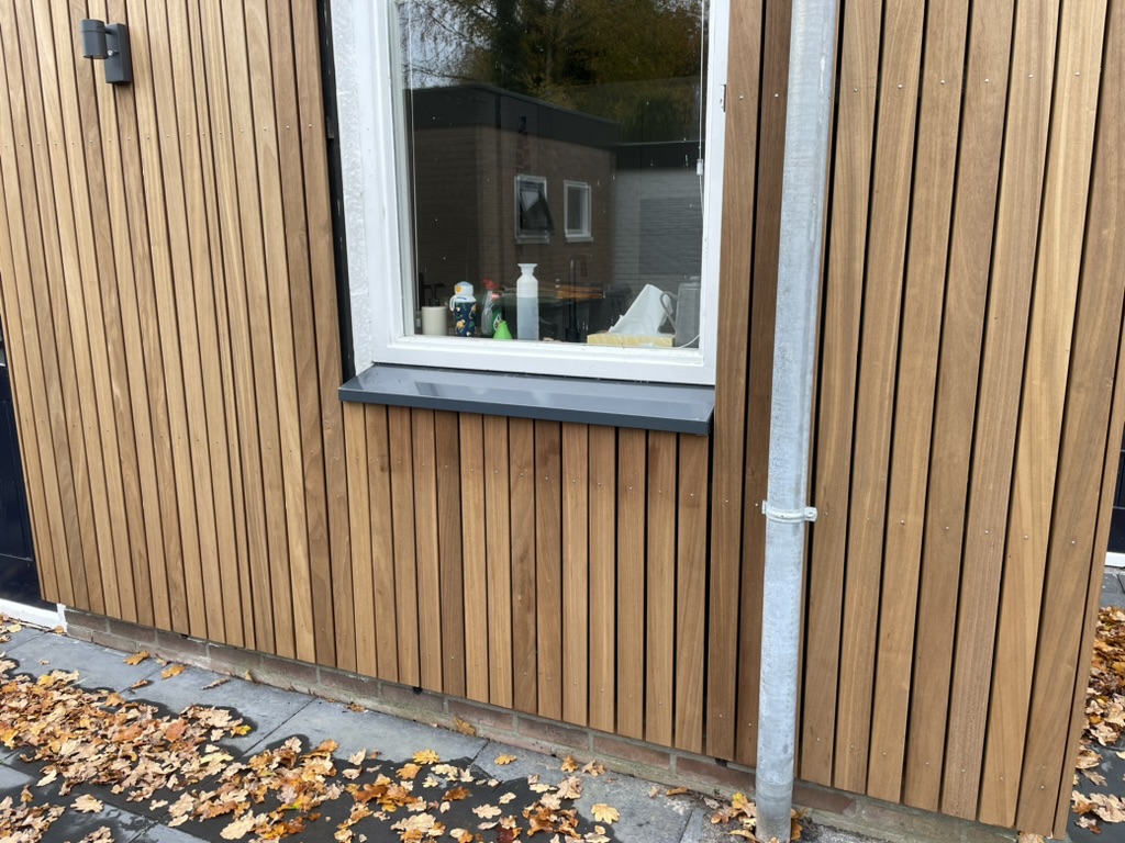 Strakke antraciet overzetvensterbank op een tuinkamer met houten gevelbekleding